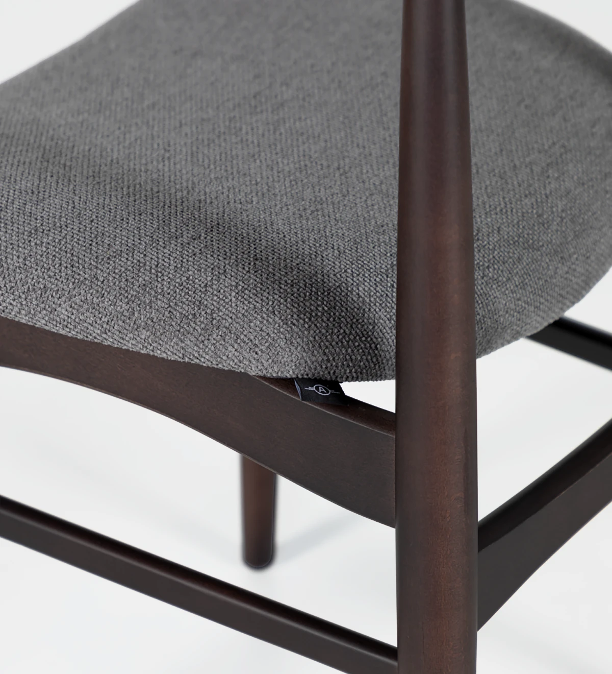 Chaise en bois de frêne couleur brun foncé avec assise recouverte de tissu.