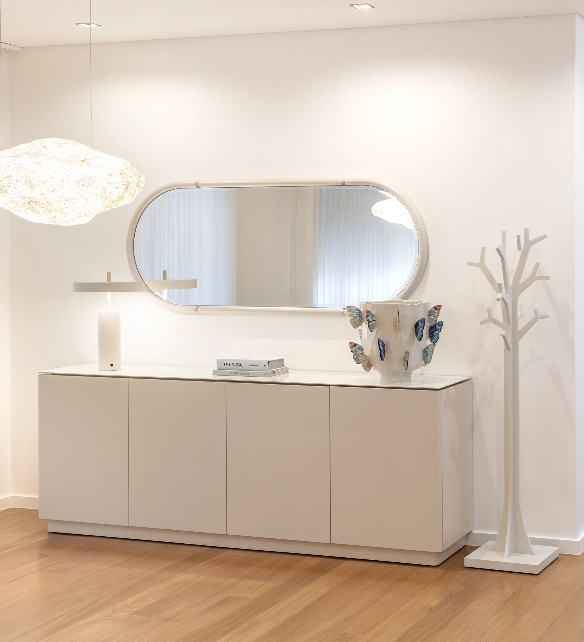 Miroir Mónaco ovale mural au-dessus d'un buffet blanc avec lampe et vase décoratif