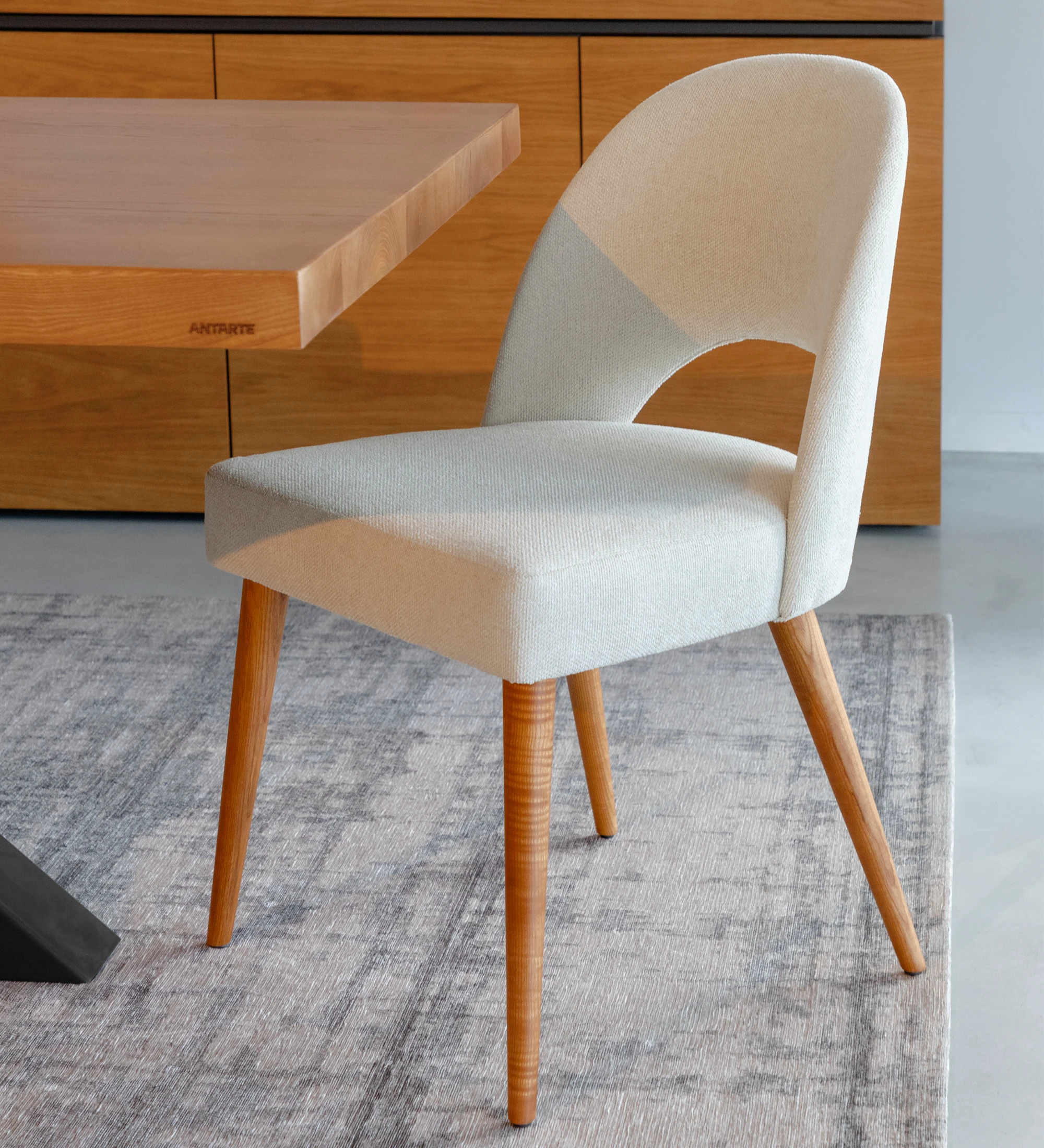 Chaise rembourré en tissu, avec pieds en bois couleur miel.