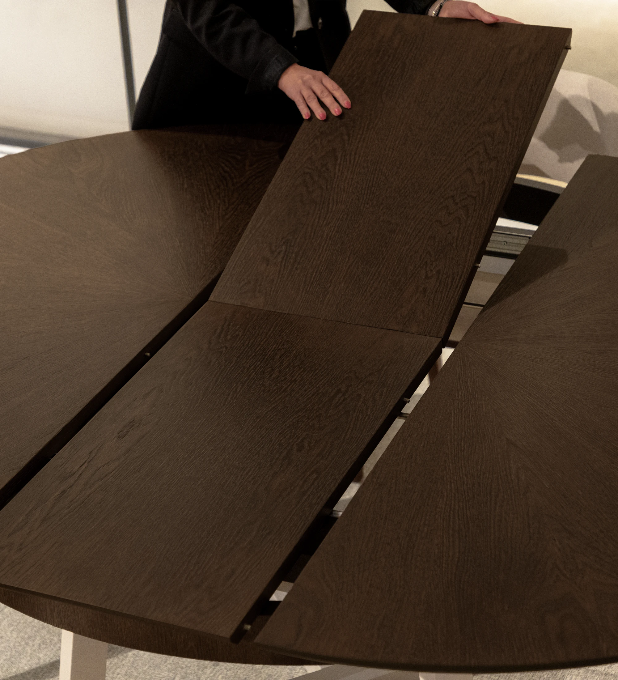 Mesa de comedor redonda extensible con tablero en roble nogal y pies lacados perla.