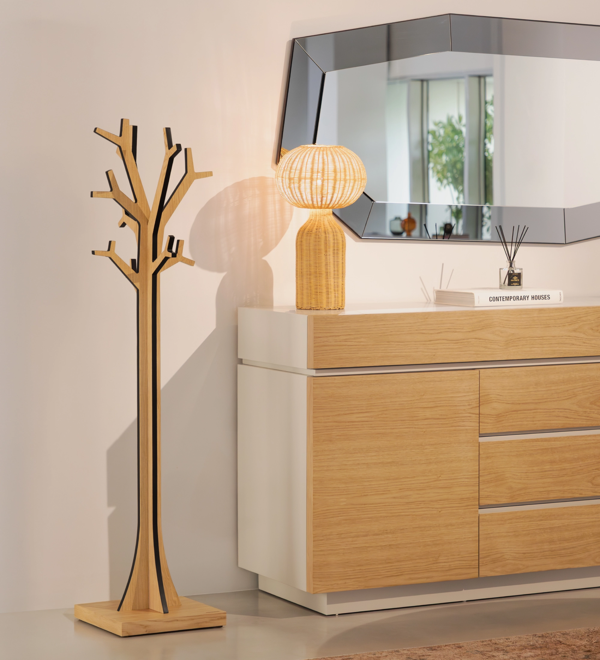 Porte-manteau en bois en forme d'arbre à côté d'un buffet, lampe et miroir