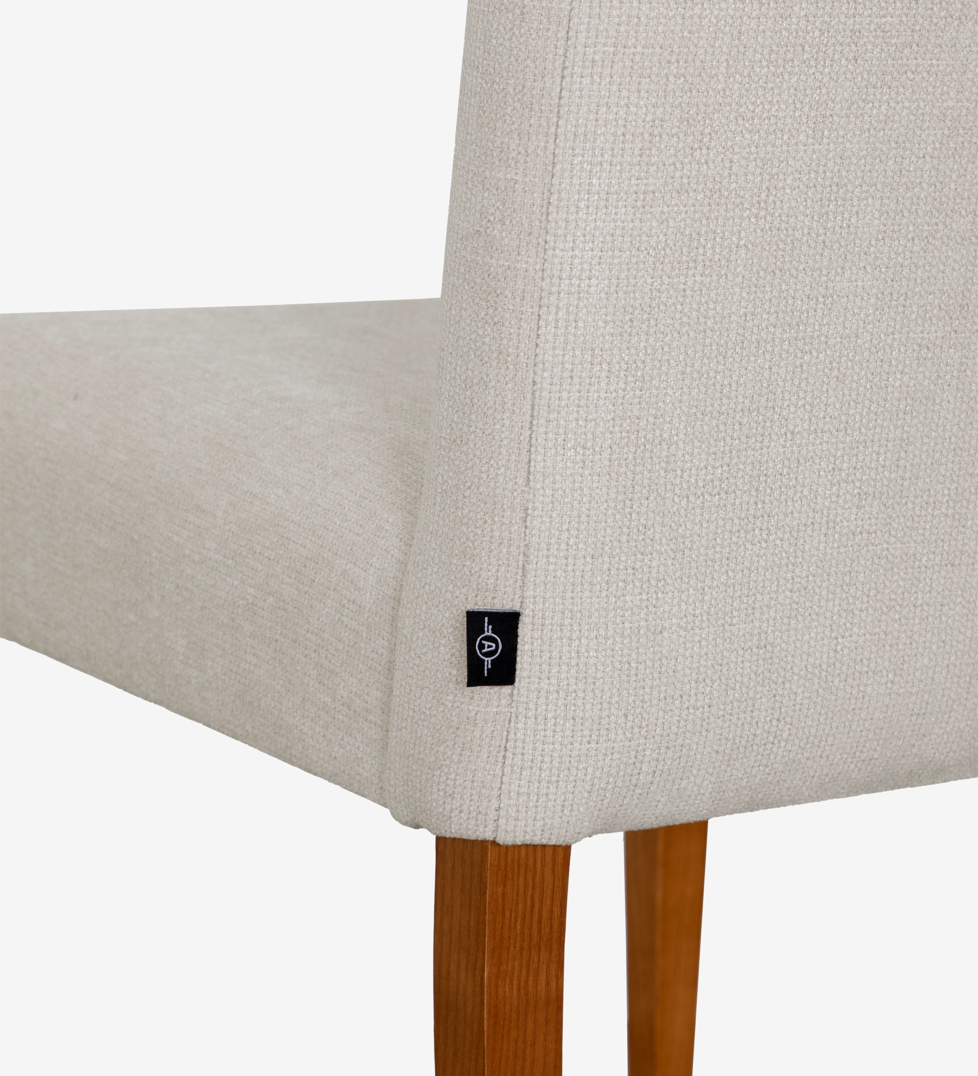 Silla tapizada en tela beige, con patas de madera color miel.