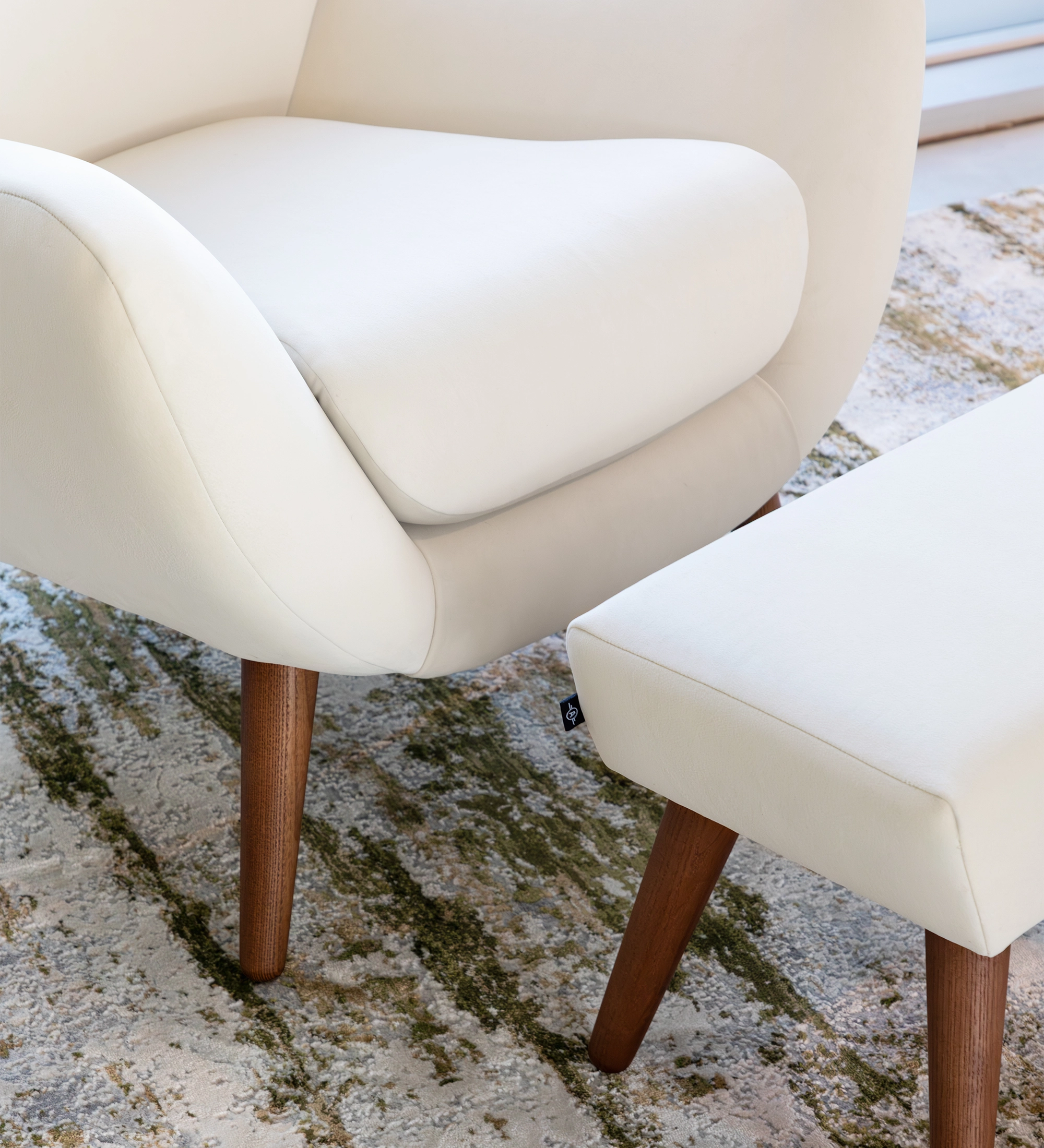 Oslo armchair upholstered in pearl fabric with walnut-stained ash wood legs.