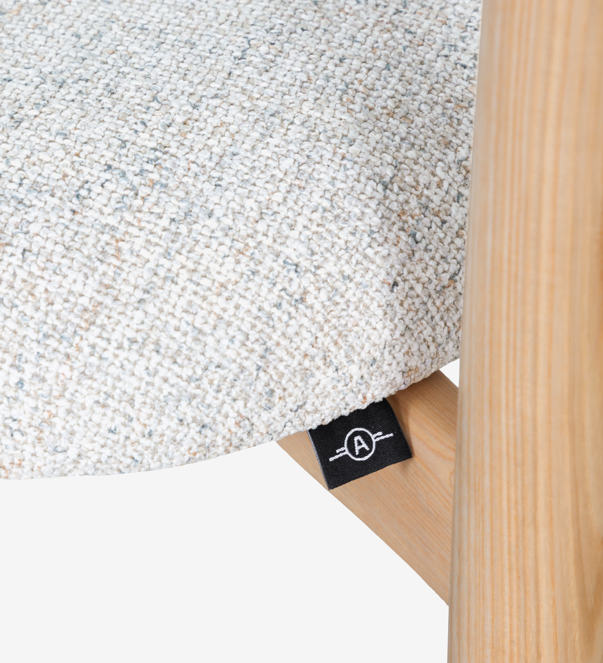 Silla de madera de fresno en color natural, con asiento y respaldo tapizados en tejido perla.