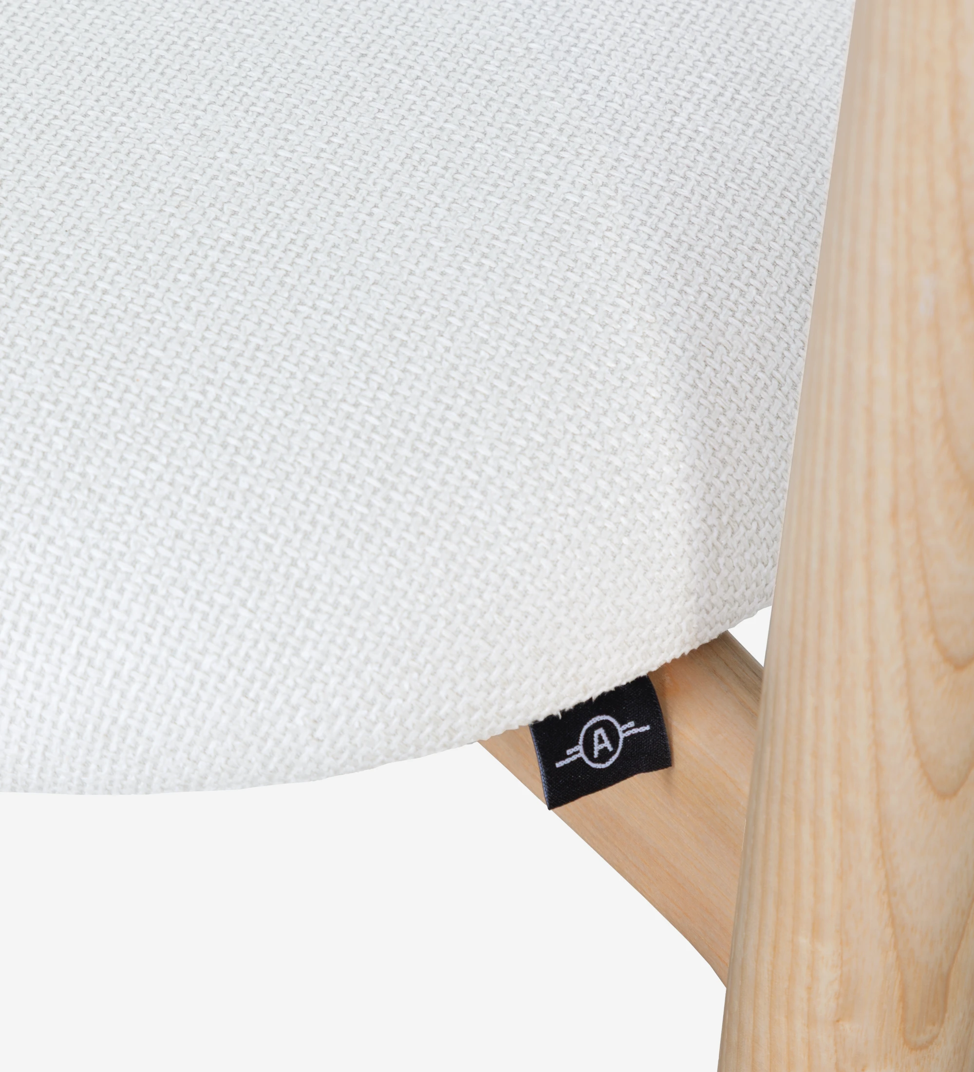 Silla de madera de fresno en color natural, con asiento y respaldo tapizados en tejido blanco.