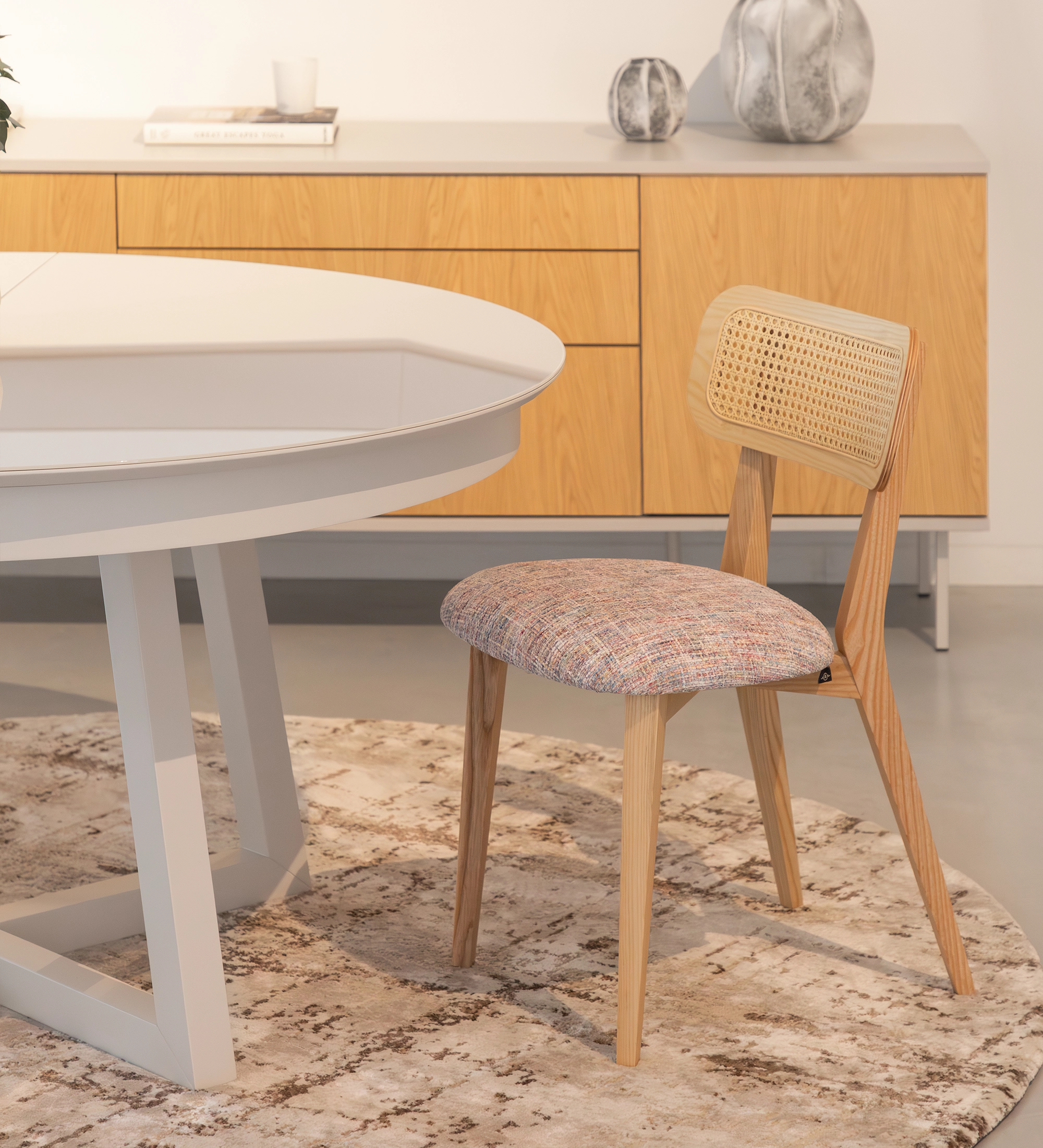 Silla de madera, con detalle de ratán en el respaldo y asiento tapizado en tejido multicolor, principalmente magenta