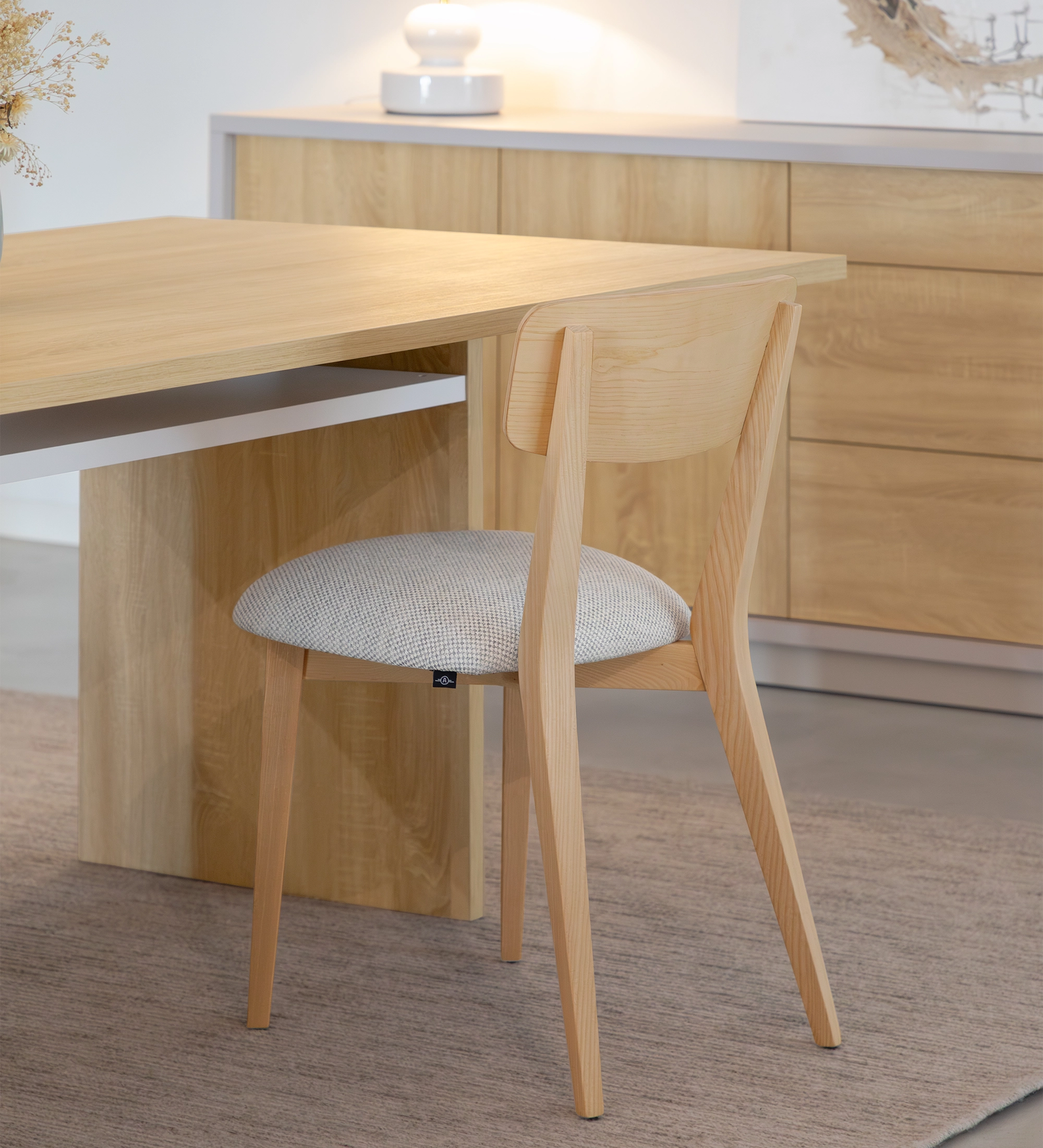 Silla en madera de fresno natural con asiento tapizado en tejido gris claro.