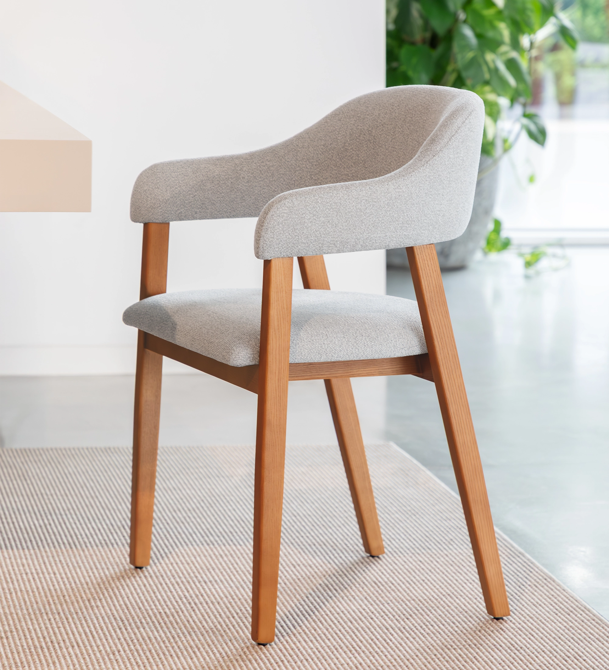 Silla con brazos, en madera de fresno color miel, con asiento y respaldo tapizados en tela gris claro