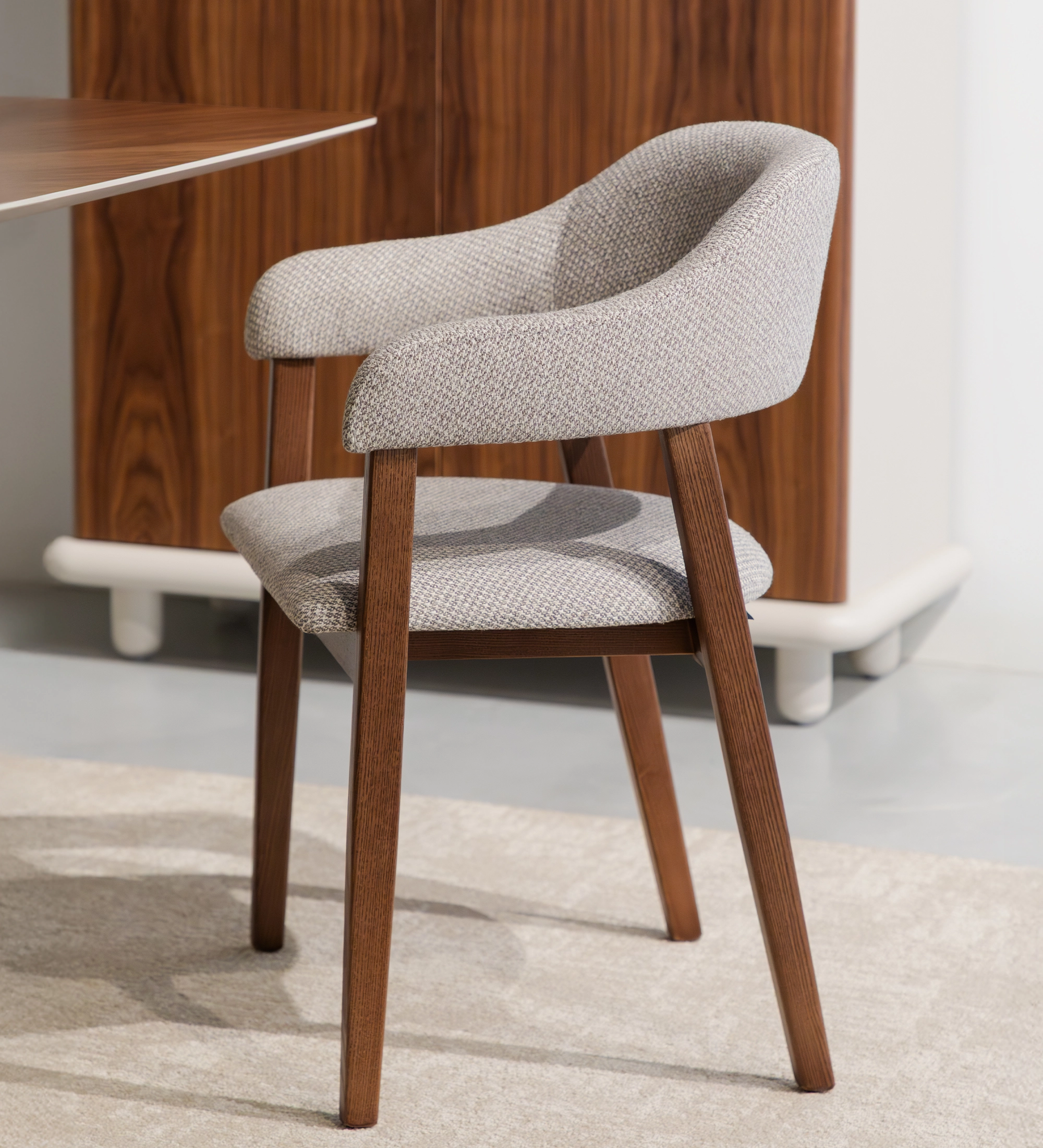 Silla Capri tapizada gris claro con patas de madera y respaldo curvado
