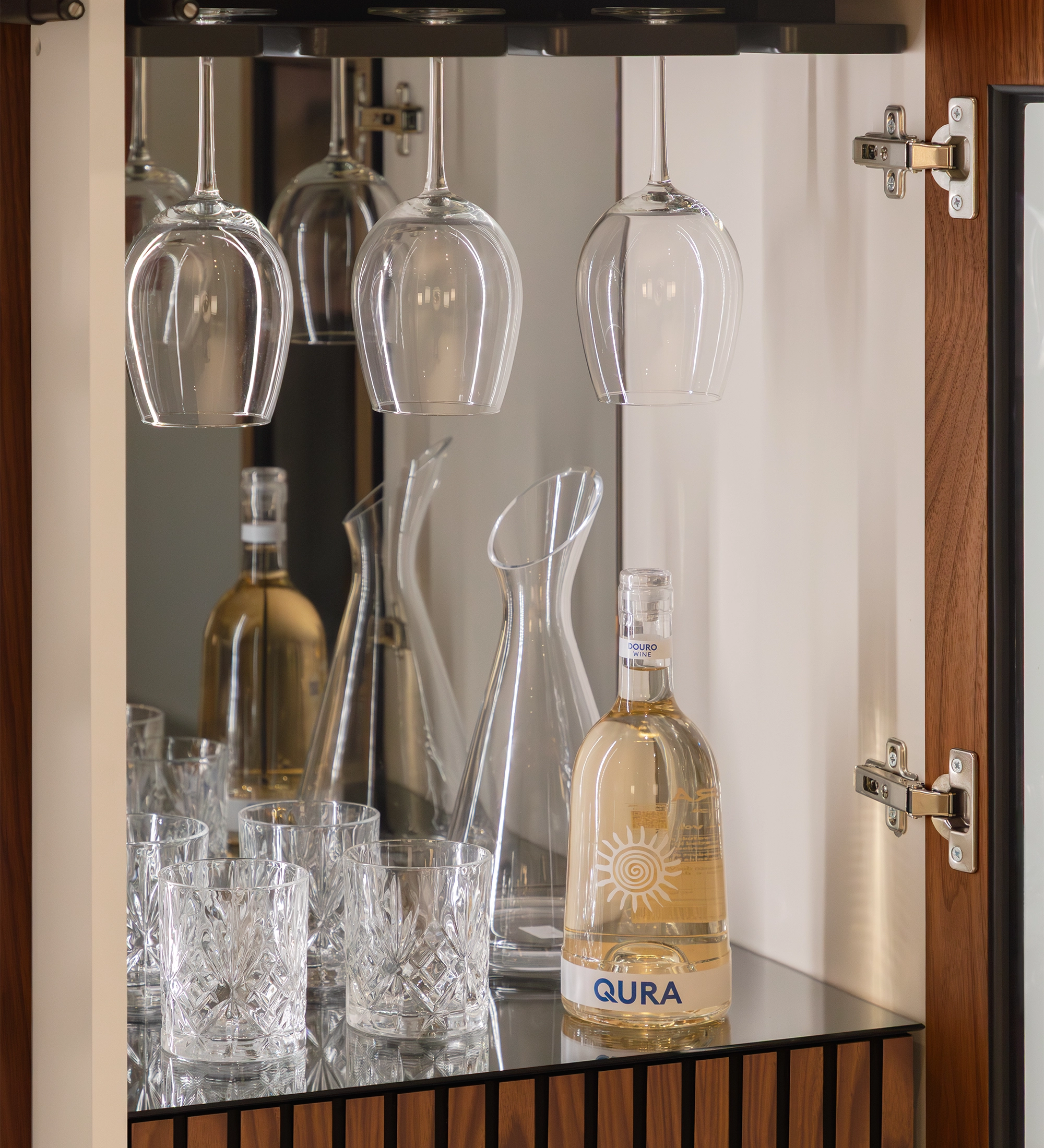 Cannes Wine Cellar interior with a bottle of white wine, crystal tumblers and hanging stemware