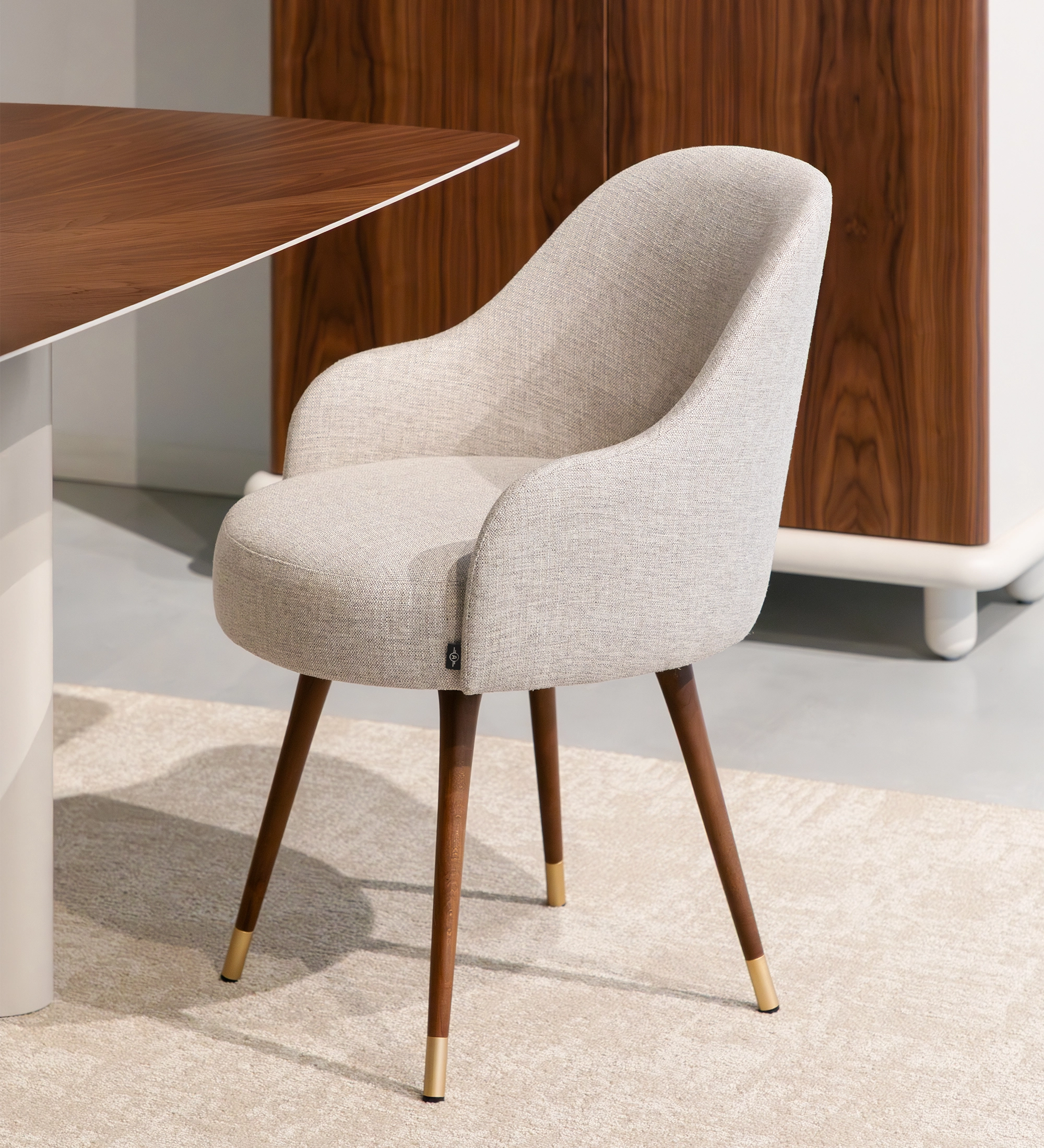 Silla Geneve tapizada beige con respaldo curvo y patas de madera con remates dorados