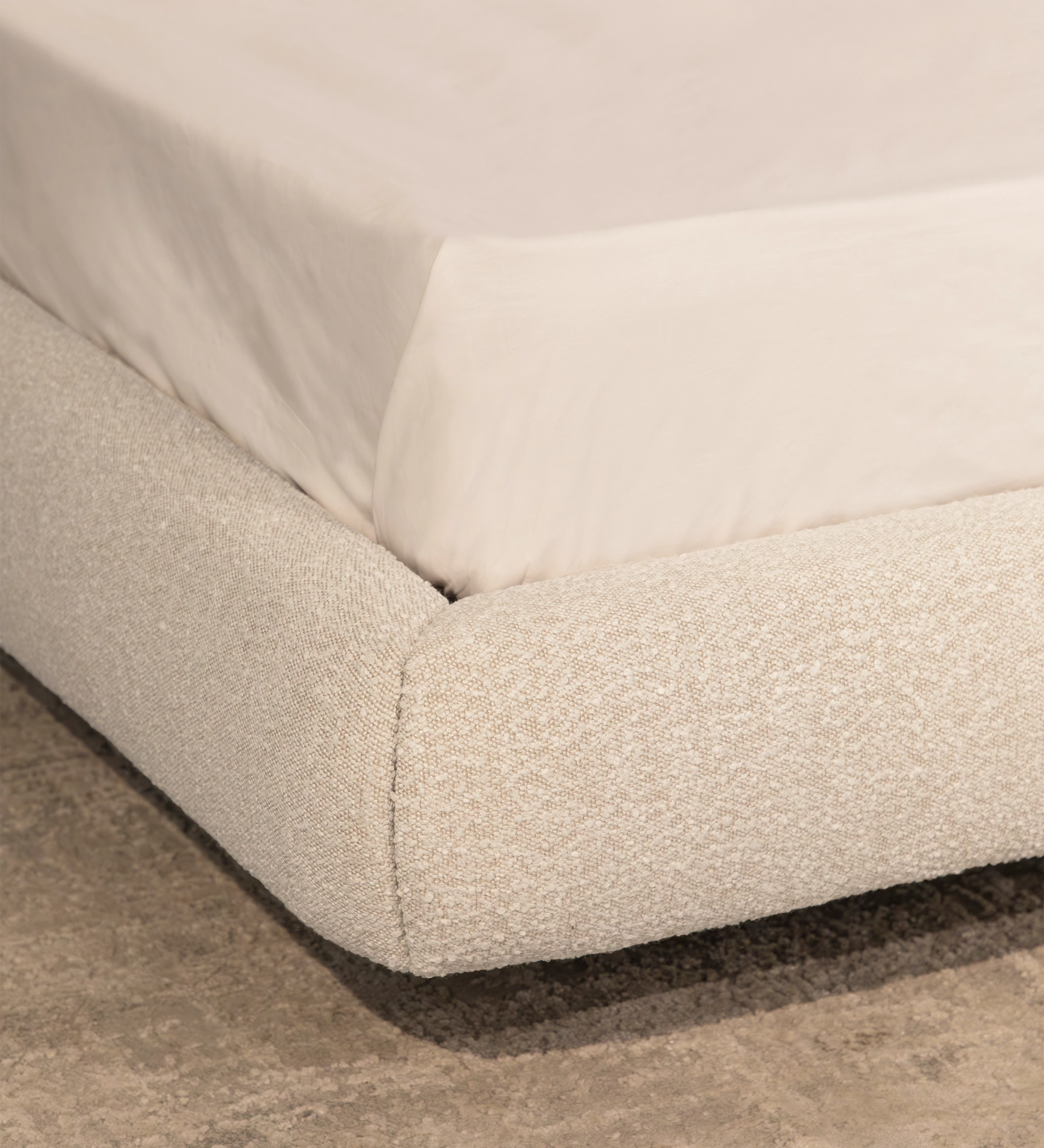Cama Doble Paris tapizada en beige, detalle de esquina con sábana blanca