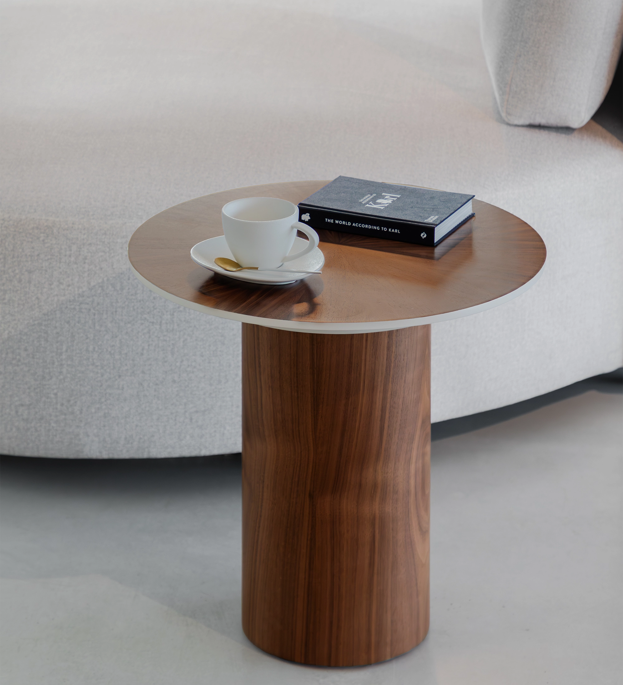 Table d'Appui Paris ronde en bois avec tasse et livre près d'un canapé gris