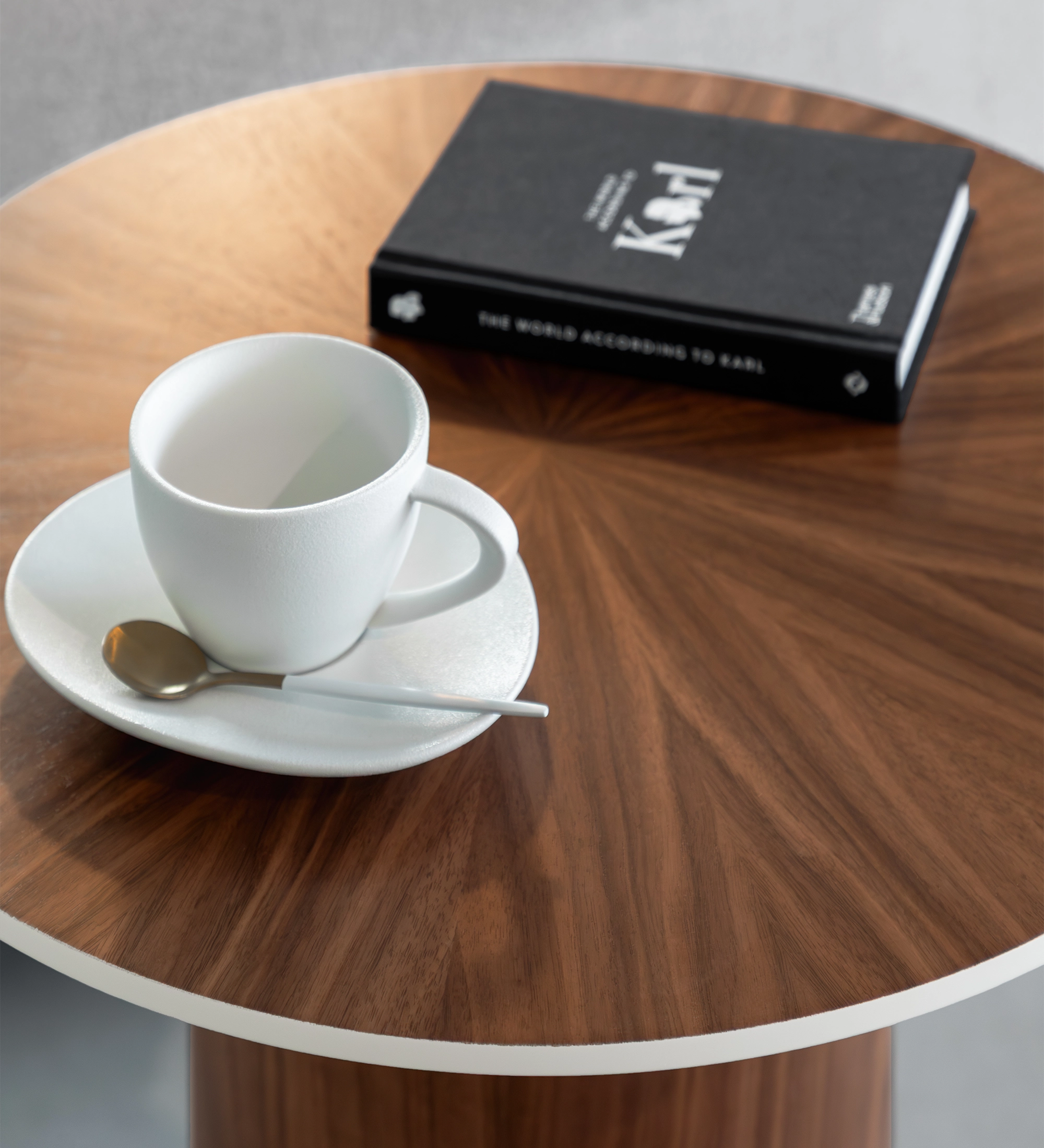Table d'Appui Paris ronde en bois avec tasse blanche, soucoupe, cuillère et livre noir