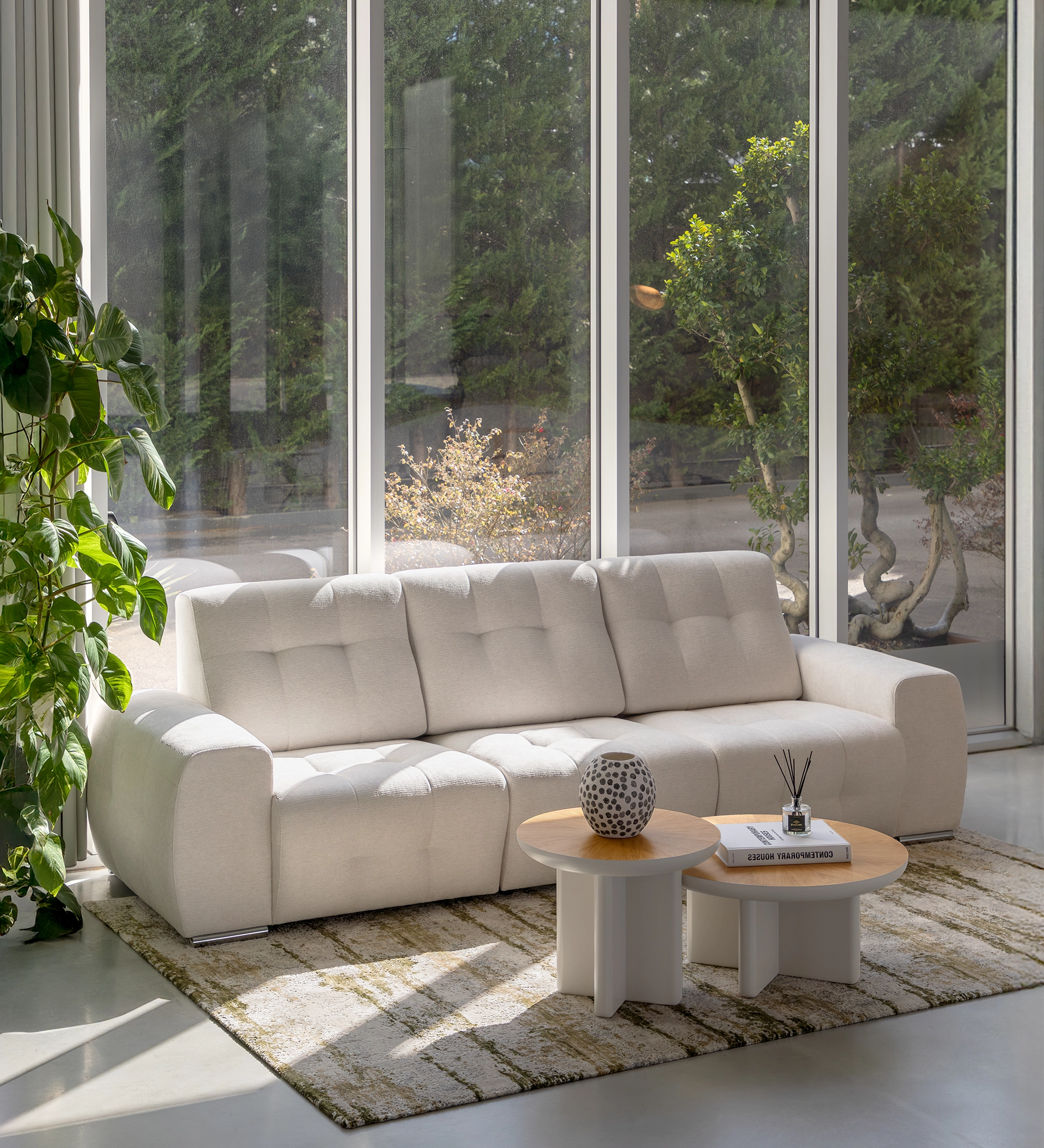 Sofá Madrid 3 plazas tapizado beige claro en salón con mesas y ventanales