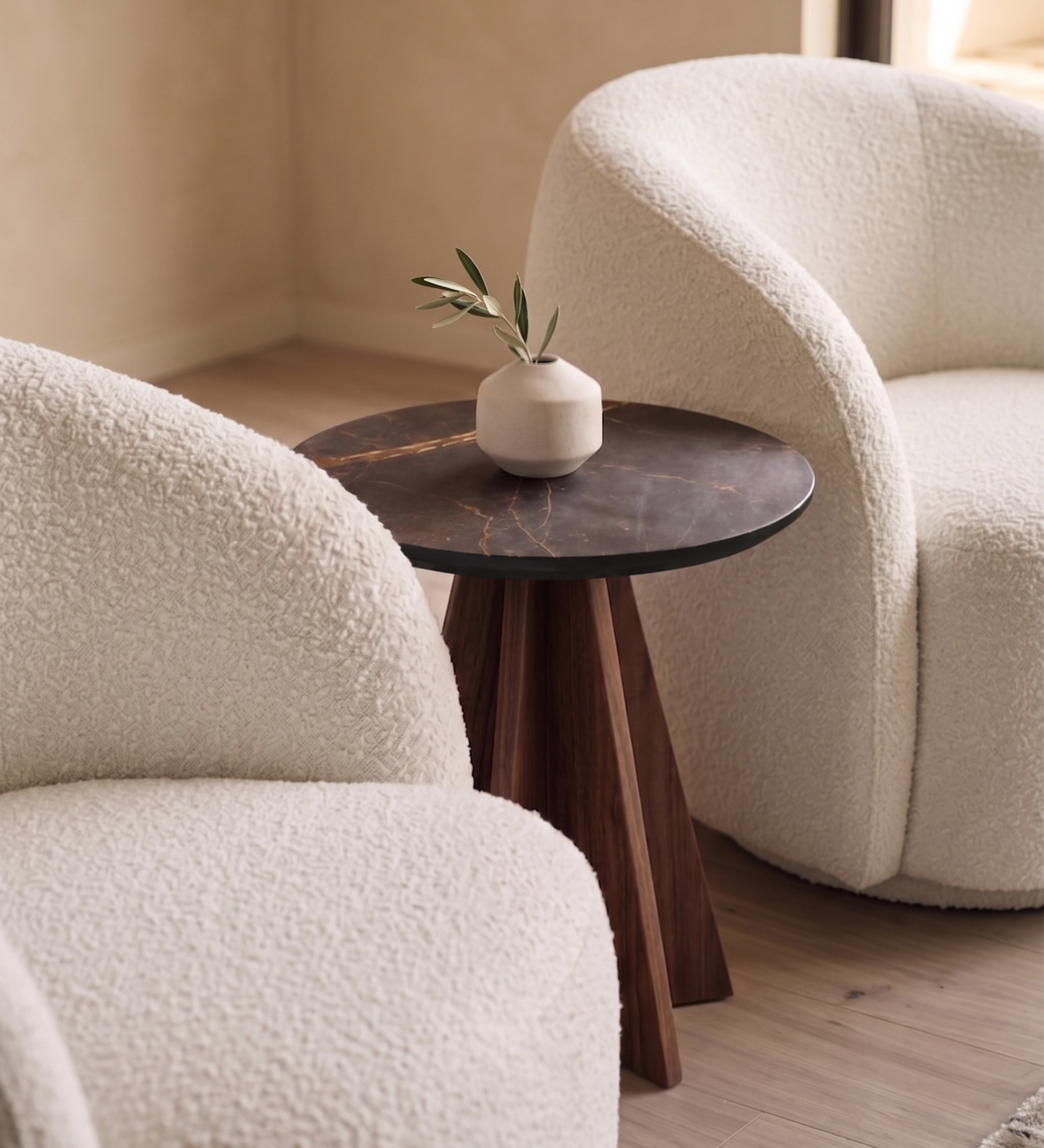 Lagos Side Table with dark marble top and wooden tripod base between cream boucle chairs