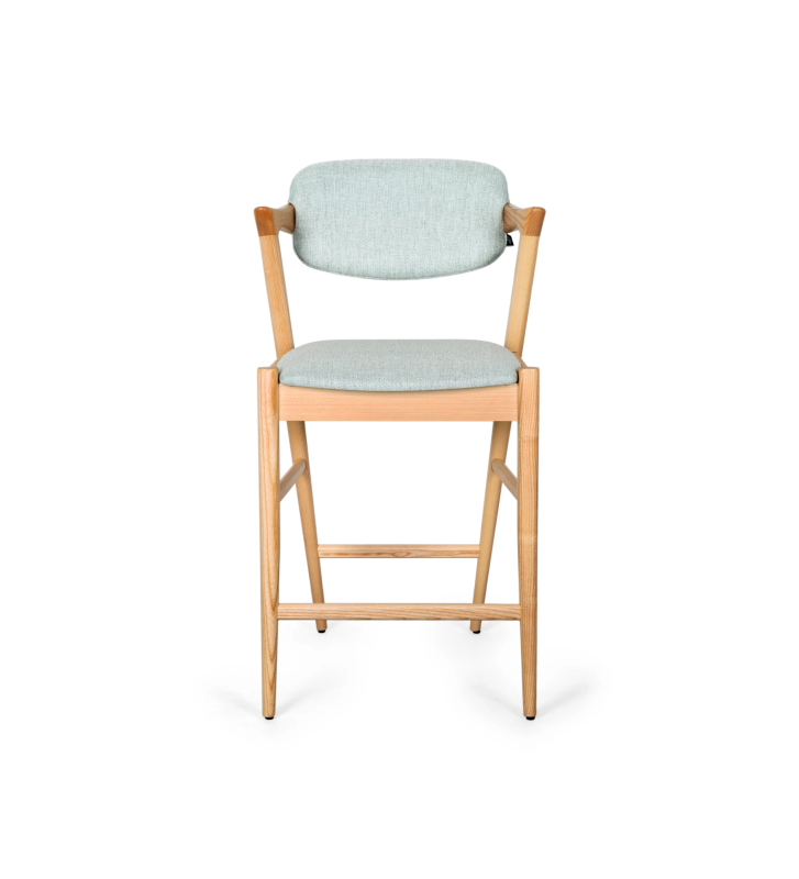 Taburete en madera de fresno color natural, con asiento y respaldo tapizado en tejido.