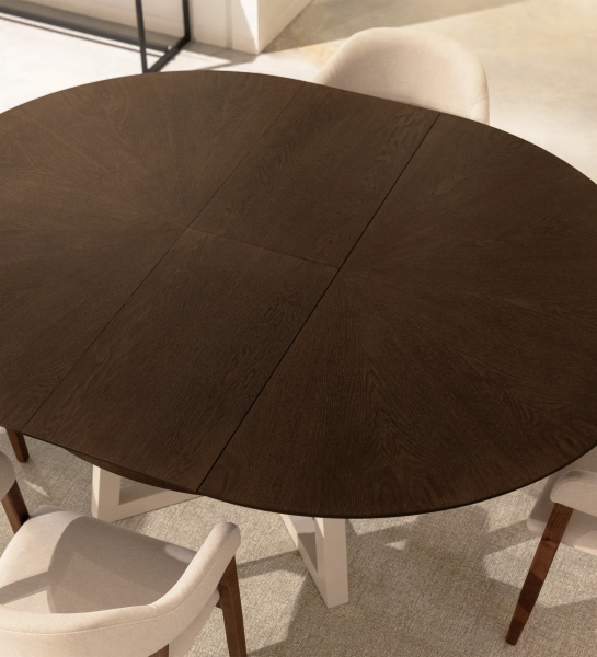 Mesa de comedor redonda extensible con tablero en roble nogal y pies lacados perla.