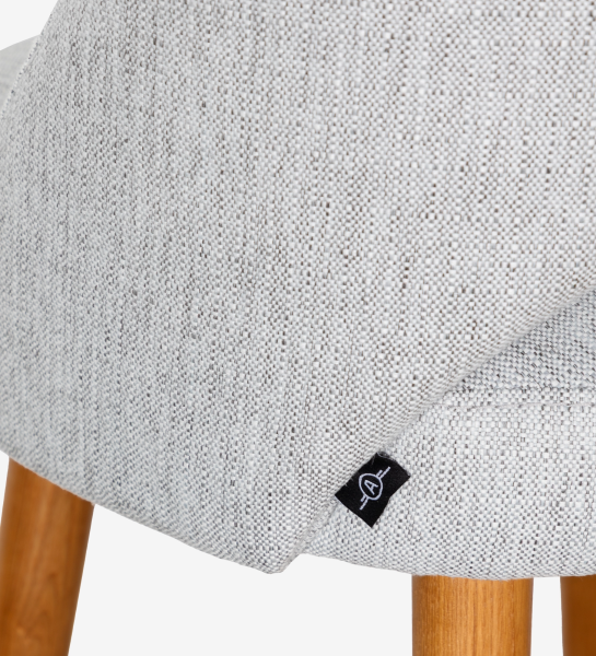 Taburete tapizados en tejido gris claro, con patas de madera color miel.