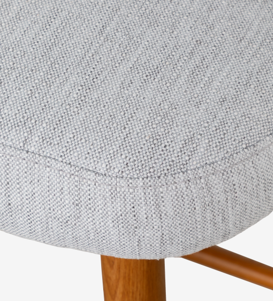 Taburete tapizados en tejido gris claro, con patas de madera color miel.