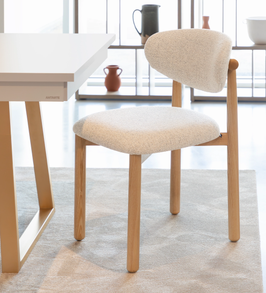 Silla de madera de fresno en color natural, con asiento y respaldo tapizados en tejido perla.