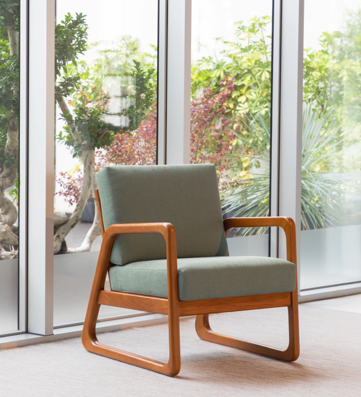 Sillón Antarte by IA tapizado en tela verde, estructura en madera color miel.