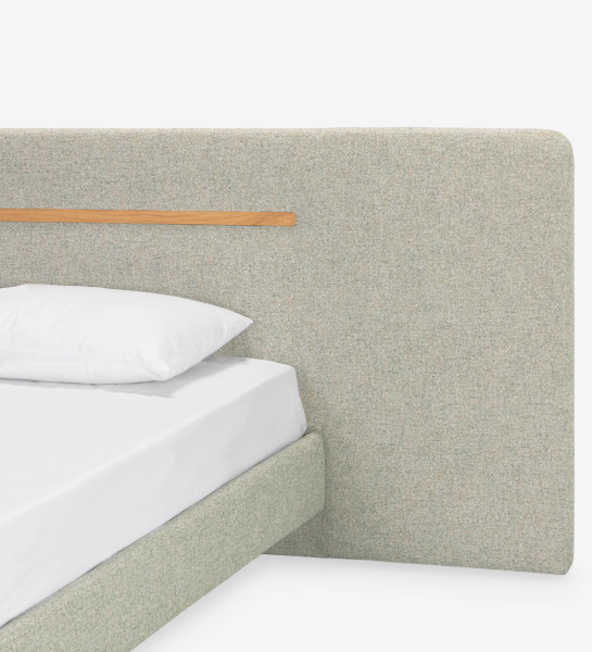Cama de casal com cabeceira e base suspensa estofada em tecido verde, pormenor em carvalho natural.