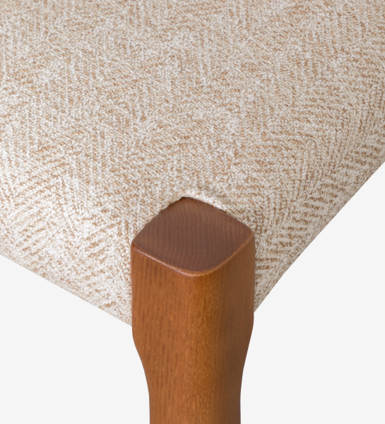 Chair in honey colored ash wood with beige fabric upholstered seat.