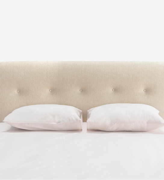 Cama de casal com cabeceira curta, estofada a tecido bege.