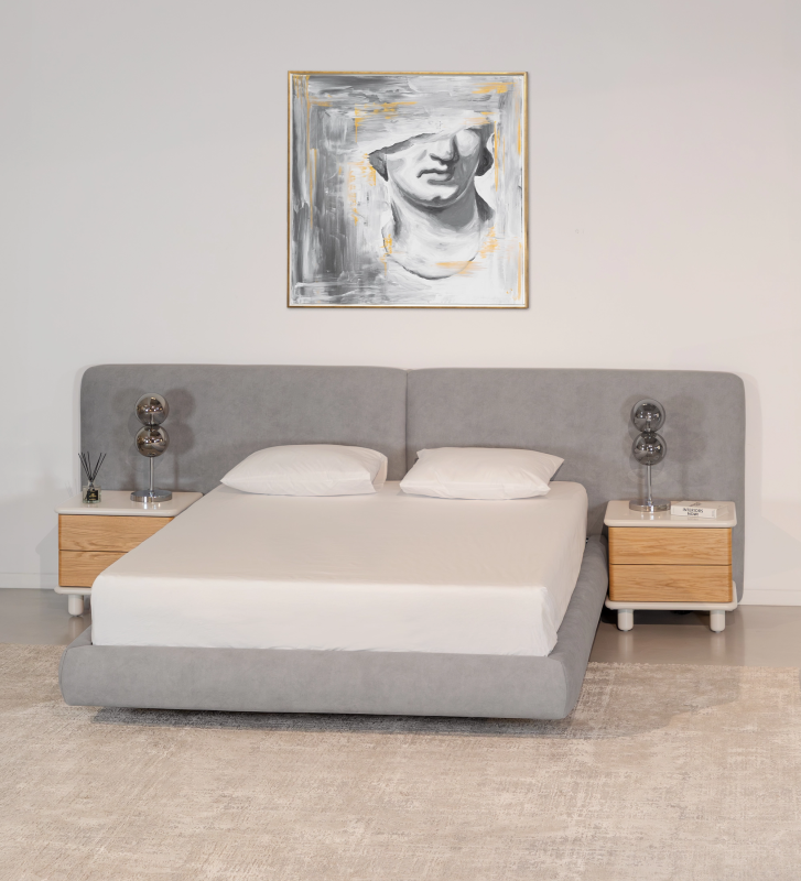Cama de matrimonio con cabecero dividido y pie de cama suspendido, tapizada en tejido gris.