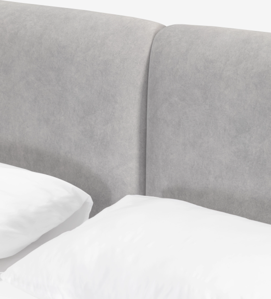 Cabecero tapizado gris claro de cama doble con almohadas blancas