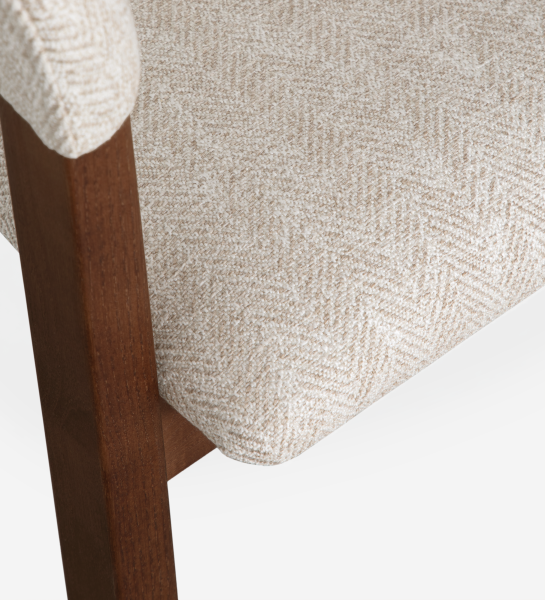 Silla con brazos, en madera de fresno color nogal, con asiento y respaldo tapizados en tela beige.