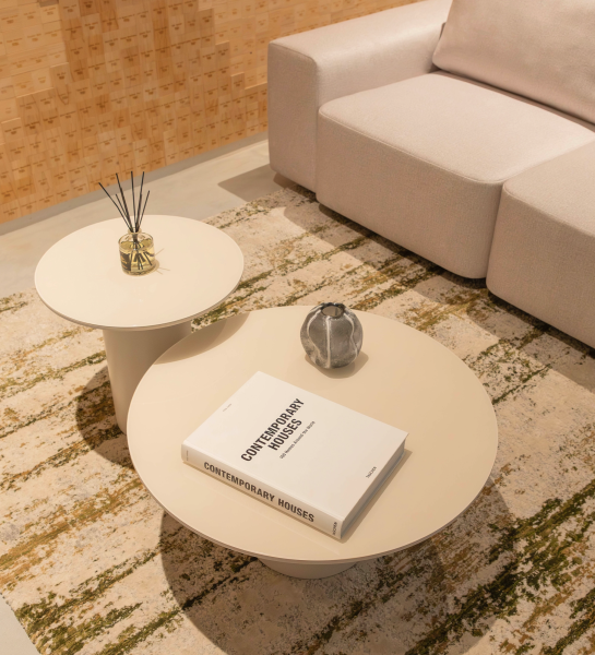 Paris Center Table round beige table with book and decorative vase beside sofa