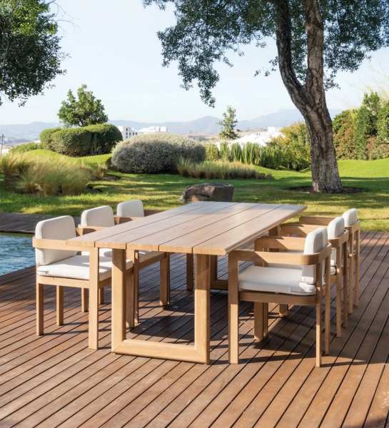 Table à manger Sines en teck avec huit chaises rembourrées sur terrasse en bois
