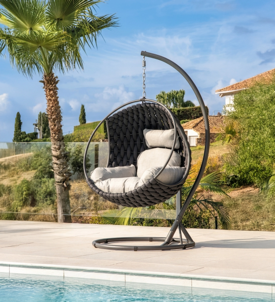 Sillón columpio Comporta tejido oscuro con cojines claros junto a piscina